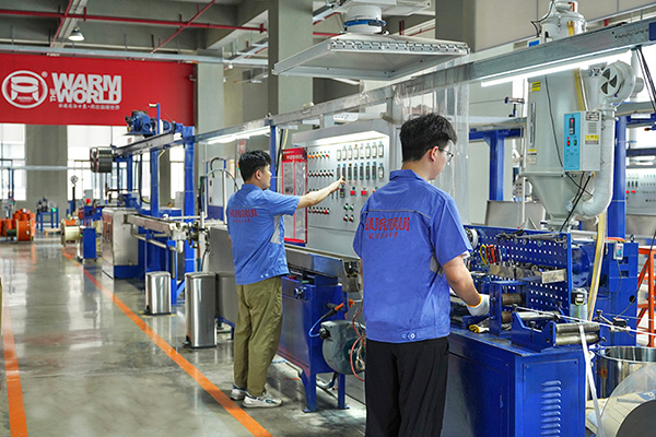 工人在操作電伴熱帶護(hù)套擠出設(shè)備。 環(huán)瑞電熱供圖